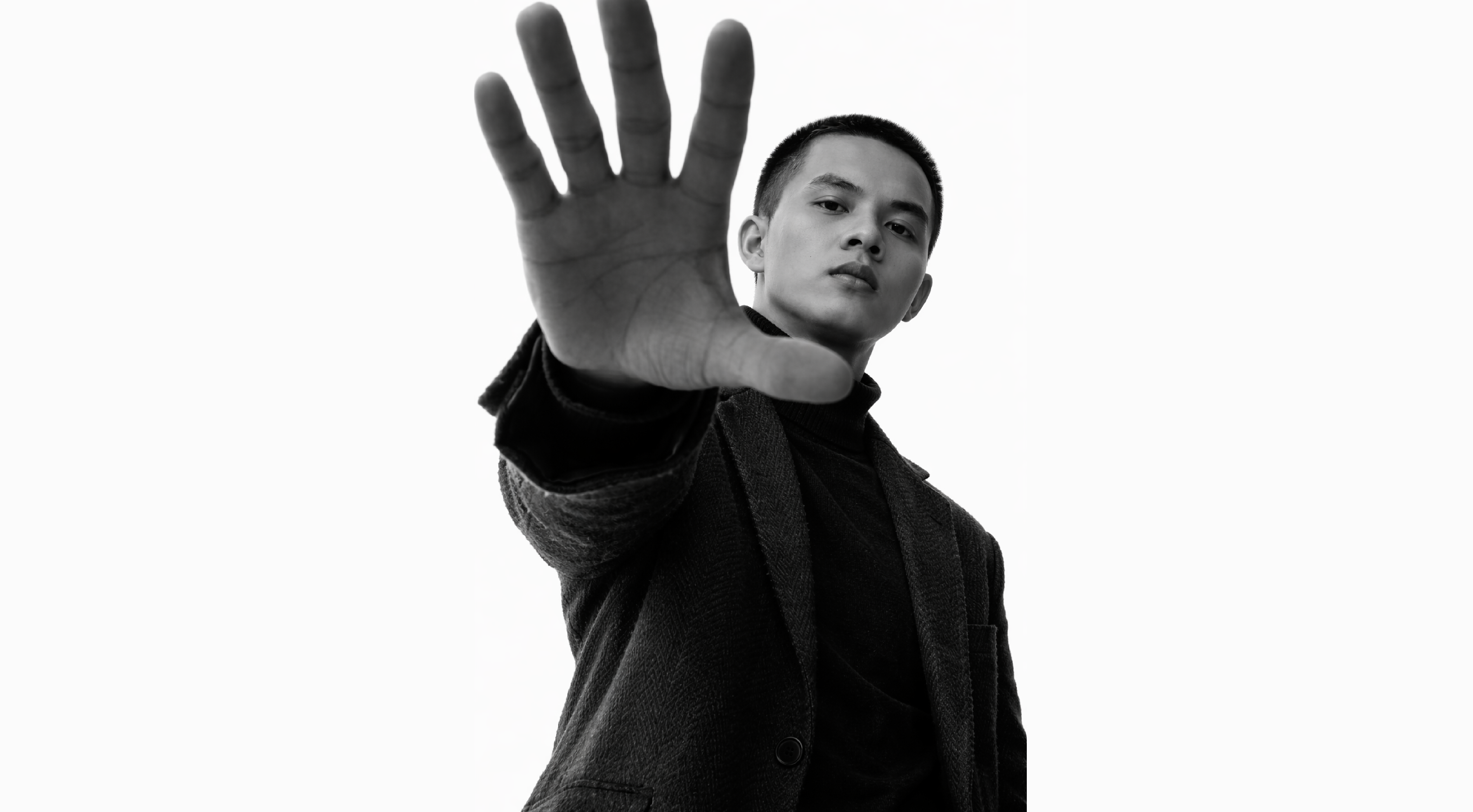 黄冠文伸手面向镜头的黑白肖像